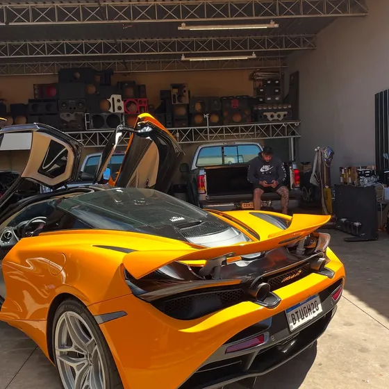 Traseira de uma McLaren 720S laranja dentro do estúdio