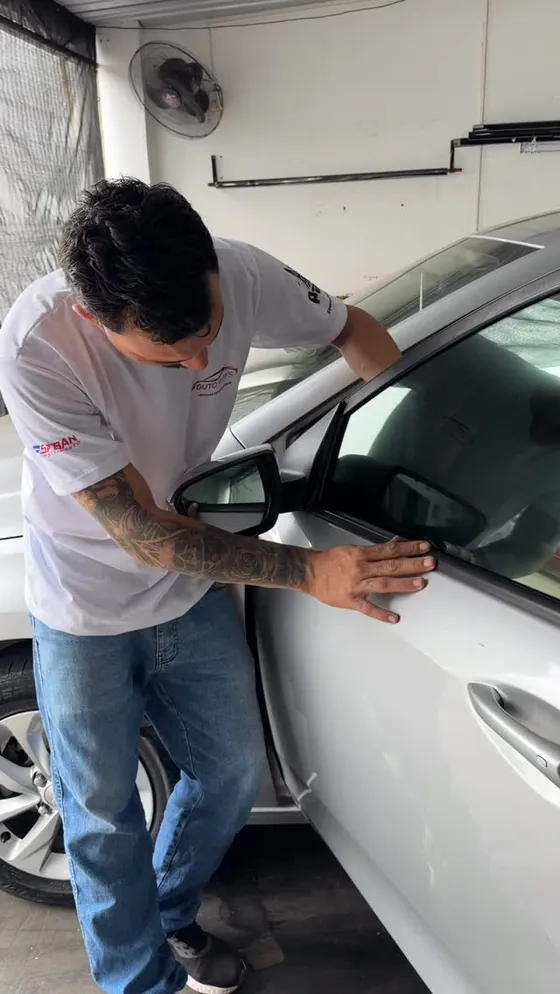 Guto aplicando película na porta de um carro